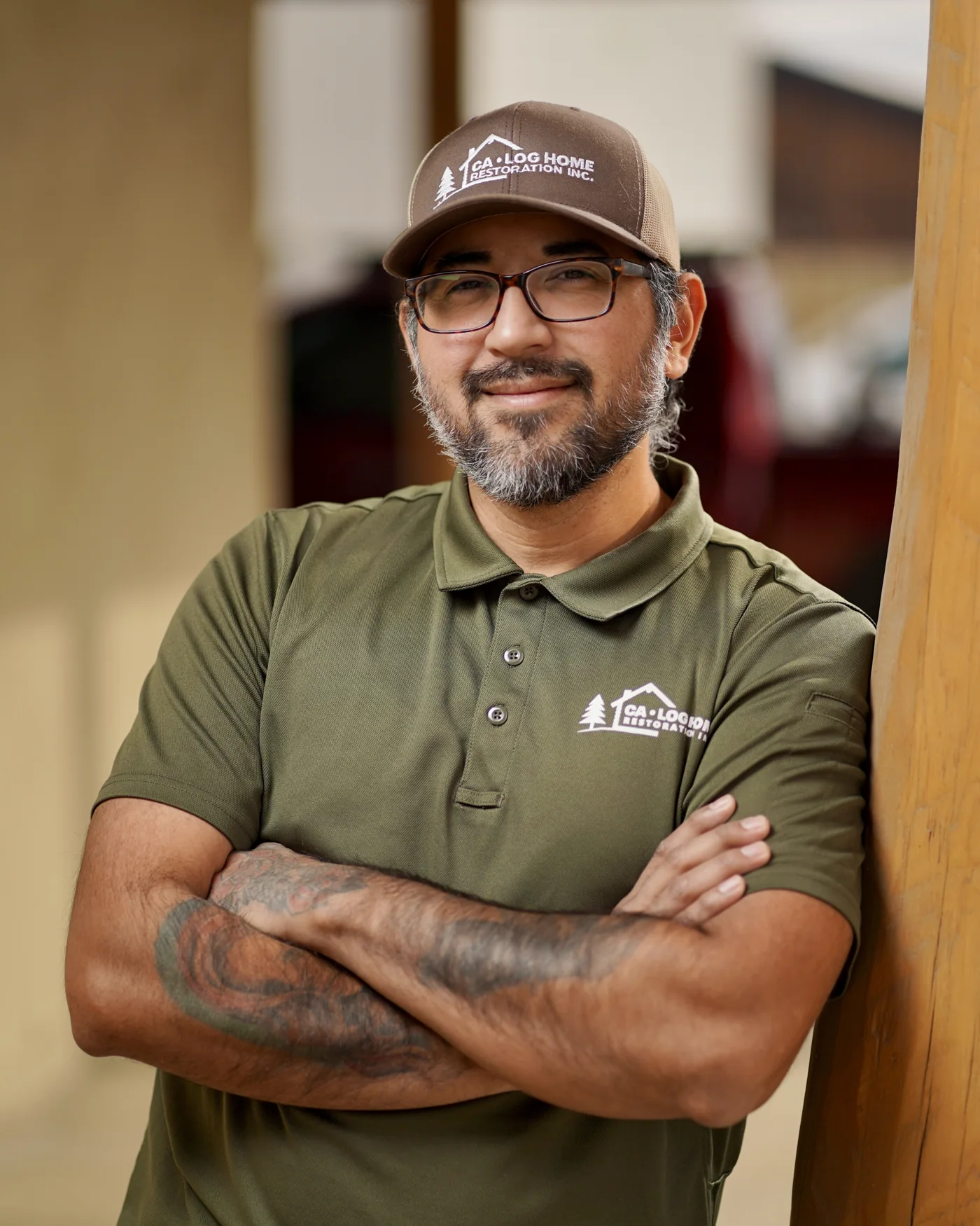 A smiling man in a work cap with folded arms