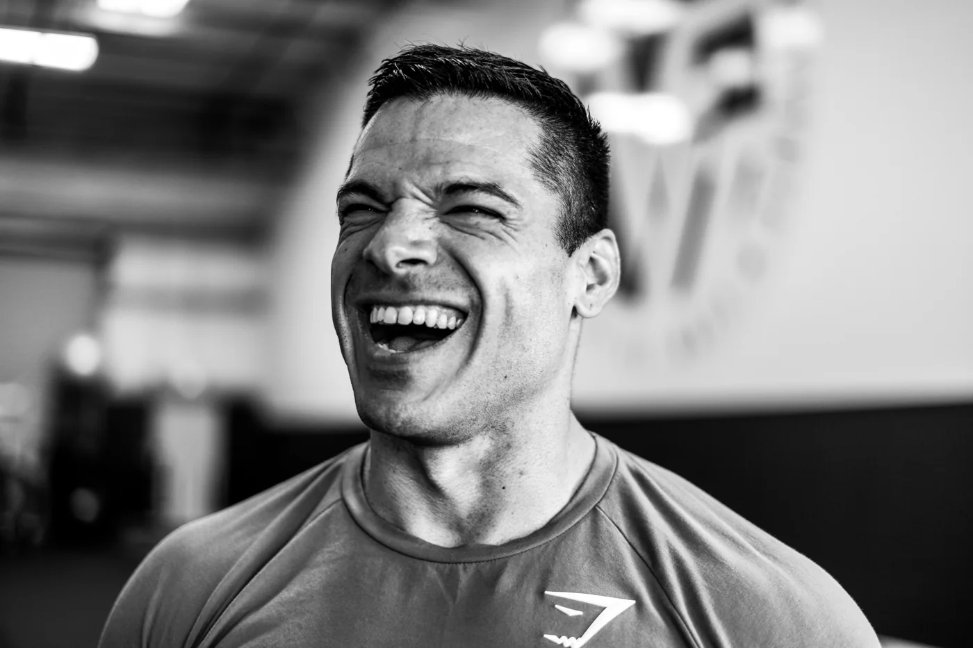 Black-and-white portrait of a man laughing in a gym