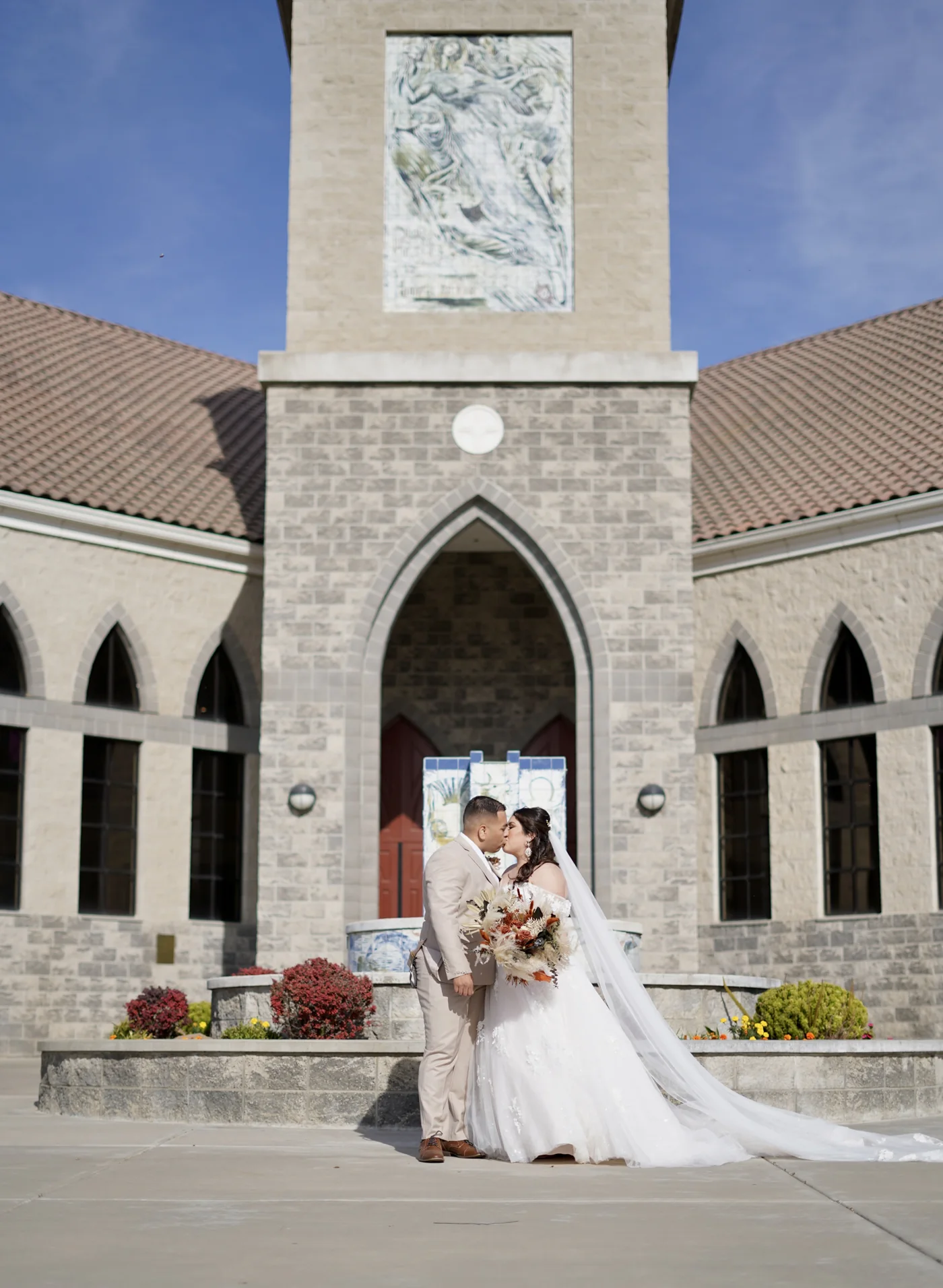 A wedding couple in front of a tall stone church