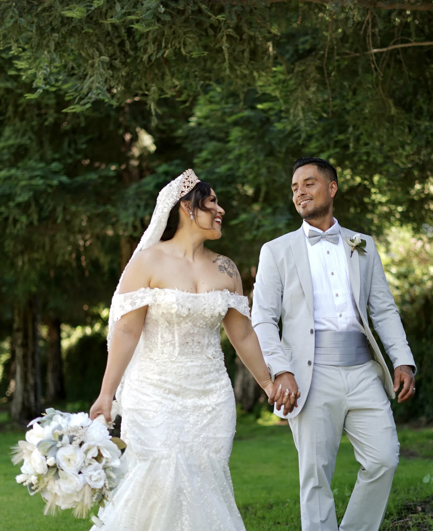 Bride and groom holding hands in a green garden
